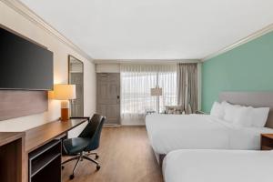 a hotel room with two beds and a desk at Comfort Inn & Suites Ormond Beach Oceanfront in Ormond Beach