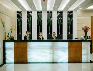 three women sitting at a counter in a lobby at Oryza Hotel in Santiago City