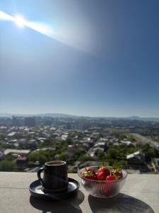 a cup of coffee and a bowl of strawberries on a ledge at Ines’s sweet home in Yerevan