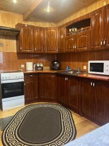 a kitchen with wooden cabinets and a rug on the floor at Котедж "Барвінок" in Verkhovyna
