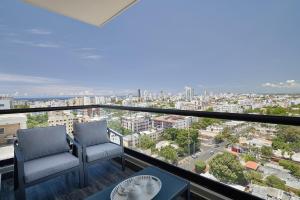 Un balcón con dos sillas y vista a una ciudad. en ®{PANO~VIEW~Experience} @DowntownSD PoolGym2BR, en Ensanche Quisqueya