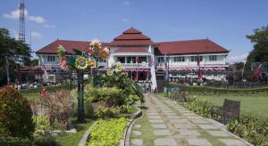 a large white building with a garden in front of it at Sunrise Hotel in Malang
