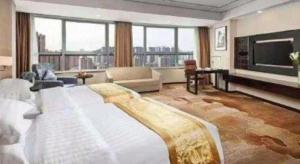 a large bedroom with a large bed and a living room at Ramada by Wyndham Wuhu in Wuhu