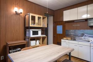 a kitchen with white cabinets and a table and a microwave at rinne 2nd living Nasu Forest in Wada