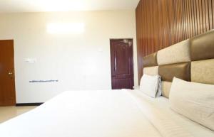 a bedroom with a large bed with a wooden headboard at Collection O MKU Madurai Formerly Mpl Elite in Samayanallūr