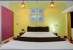 a bedroom with a large bed with yellow walls at Hotel O Palasuni Bridge Bhubaneswar Formerly Ganpat in Mancheshwar