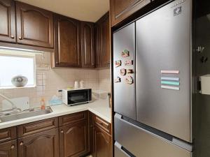 a kitchen with wooden cabinets and a stainless steel refrigerator at Direct to Shinjuku 15 mins Up to 6Guests in Tokyo