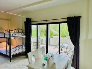 a room with a balcony with a bed and a table at M&N Guesthouse Kata in Kata Beach