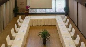 a room with white tables and chairs and a potted plant at Chengdu Nine Point Art Hotel in Chengdu