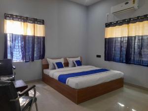 a bedroom with a bed with blue sheets and curtains at Hotel O Samrat Palace in Bārang