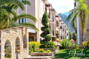 a building in a resort with palm trees and flowers at Valis Resort Hotel in Volos