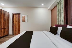 a bedroom with a large white bed and a wooden door at Hotel O 3 Bros in Sohāna +21 photos