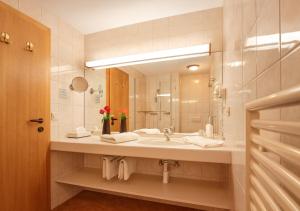a bathroom with a sink and a mirror at Country Wellnesshotel Bündnerhof in Samnaun +59 photos