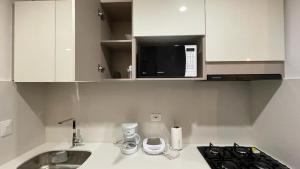 a white kitchen with a sink and a microwave at Nuevo y lujoso Aparta suite en el exclusivo sector de playa salguero Santa Marta in Santa Marta