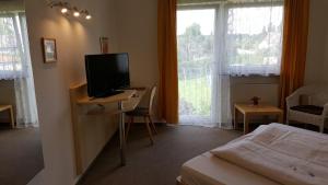 Schlafzimmer mit einem Bett und einem TV auf einem Schreibtisch in der Unterkunft Landgasthof Traube in Heidenheim