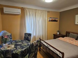 ein Schlafzimmer mit einem Bett und einem Stuhl und einem Fenster in der Unterkunft Unique Mailo cottage in Riga