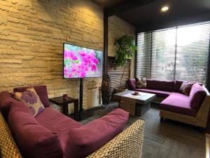 a living room with purple couches and a tv at Hotel Bougainvillea Akebonobashi in Tokyo