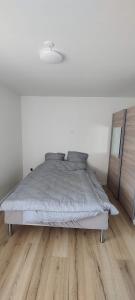 a white bedroom with a bed and a wooden floor at Værelser i Ølst, Randers SV in Randers