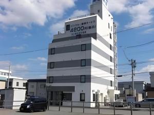 un bâtiment blanc avec une pancarte sur le côté dans l'établissement Hirosaki Ekimae Hotel, à Hirosaki
