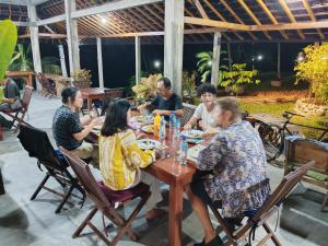 a group of people sitting around a wooden table at Pondok bluepo in Mendaya