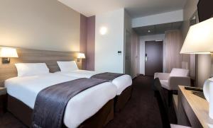um quarto de hotel com uma grande cama branca e uma secretária em Campanile Metz Nord - Talange em Talange