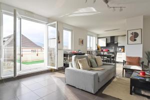 a living room with a white couch and a kitchen at L'équinox in Bourgheim