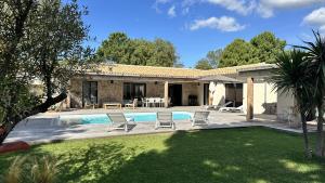 a backyard with a pool and chairs and a house at Les Villas de Fiori Di Cala Rossa in Lecci