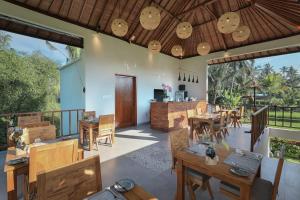 a restaurant with wooden tables and chairs and windows at Ascarya Villa Ubud in Ubud