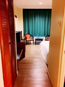 a hotel room with a bedroom with a bed and a couch at Global Hotel Labuan in Victoria Town