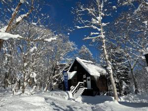 una cabaña de madera en la nieve con árboles en Casa Bell Cabin Niseko, en Niseko
