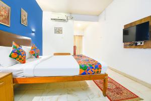 um quarto com uma cama e uma TV na parede em FabHotel Benz Destination em Candolim