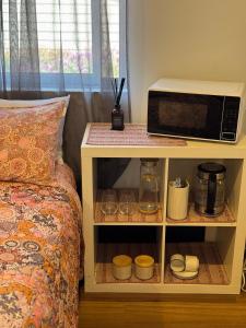a microwave on a shelf next to a bed at Toodyay Upon Avon Guest House and Gallery in Toodyay