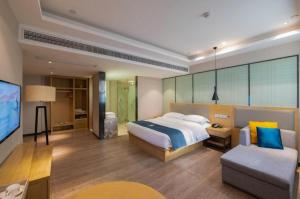 合肥市にあるEcharm Hotel Hefei Binhu Exhibition Centerのベッド、ソファ、テレビのある寝室