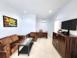 Una sala de estar con un sofá y un televisor de pantalla plana. en Toba Beach Hotel, en Tomok