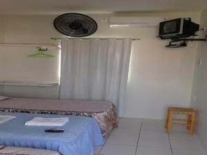 a room with two beds and a tv on the wall at Brisa da Serra Pousada EM SOBRAL-CE in Sobral