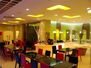 a restaurant with tables and chairs and a counter at Tomolo Hotel Wuzhan Branch in Wuhan