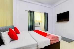 a bedroom with a large bed with red pillows at Hotel O Raama in Lucknow