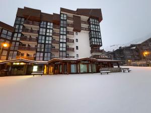 Un bâtiment dans la neige avec des bancs devant lui dans l'établissement Les appartements de Makalu Val Thorens, à Val Thorens