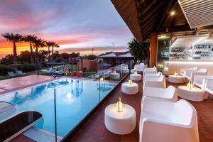 a rooftop bar with white chairs and a pool at Aparthotel Novo Resort in Novo Sancti Petri