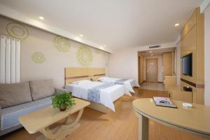 a hotel room with two beds and a couch at GreenTree Inn Chifeng Ningcheng County Bus Station Branch in Xihusutai