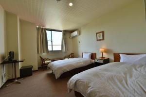a hotel room with two beds and a window at Hotel Chalet Ryuo in Yamanouchi