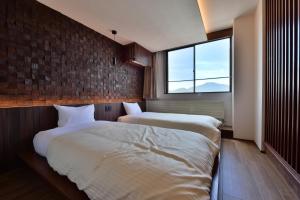 two beds in a room with a window at Hotel Chalet Ryuo in Yamanouchi