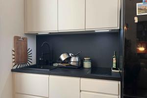 Una cocina con gabinetes blancos y una encimera negra. en Bright and comfortable stay in the heart of Lyon, en Gare des Brotteaux