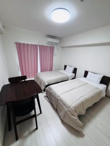 2 camas en una habitación con mesa y escritorio en U&T V Five room306, en Beppu