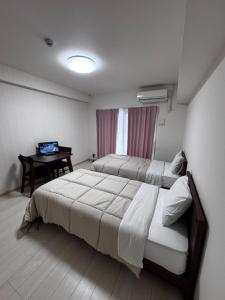 a bedroom with two beds and a desk in it at U&T V-Five Room-306 in Beppu