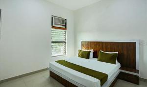 een slaapkamer met een groot bed met een houten hoofdeinde bij FabHotel Rajhans in Gurgaon