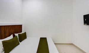 een wit bed met groene kussens in een kamer bij FabHotel Rajhans in Gurgaon