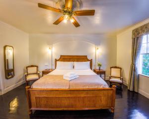 a bedroom with a bed with a ceiling fan and two chairs at Turks Head Inne in Grand Turk