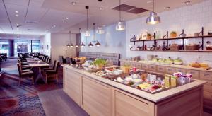 a restaurant with a long counter with tables and chairs at Clarion Collection Hotel Astoria in Hamar