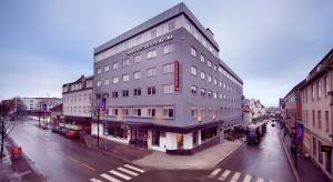 um edifício cinza alto numa rua da cidade em Clarion Collection Hotel Astoria em Hamar